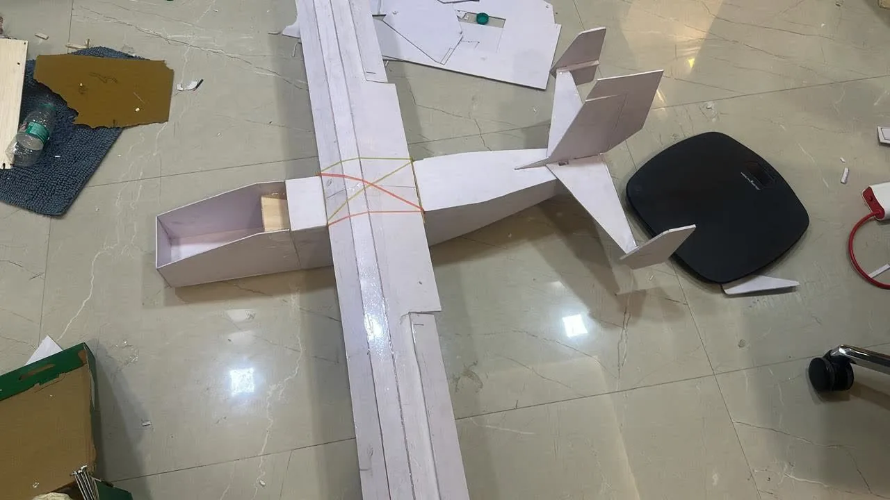 A foam-board aircraft being assembled on the floor.