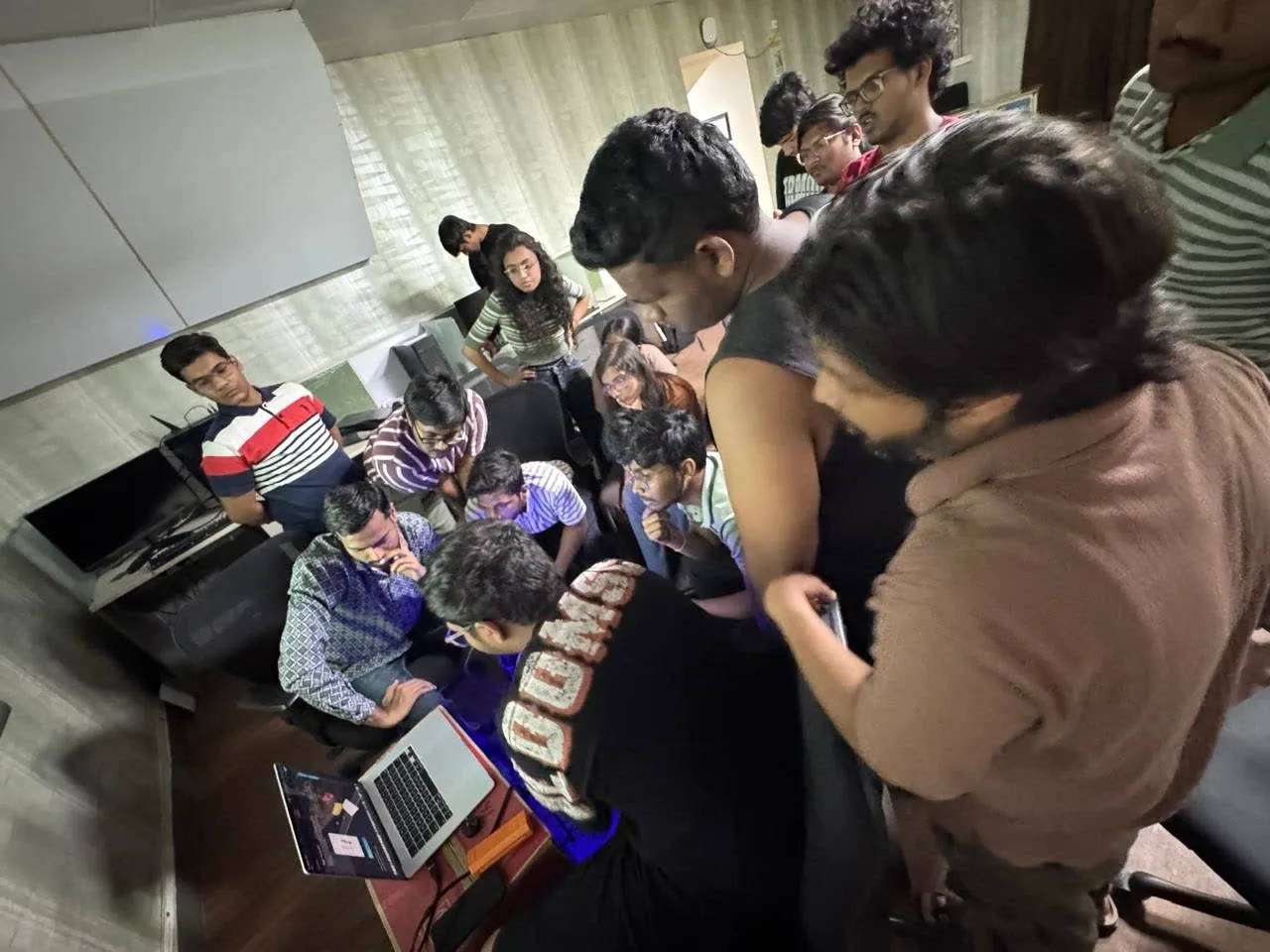 Students gathered around laptops during a session.